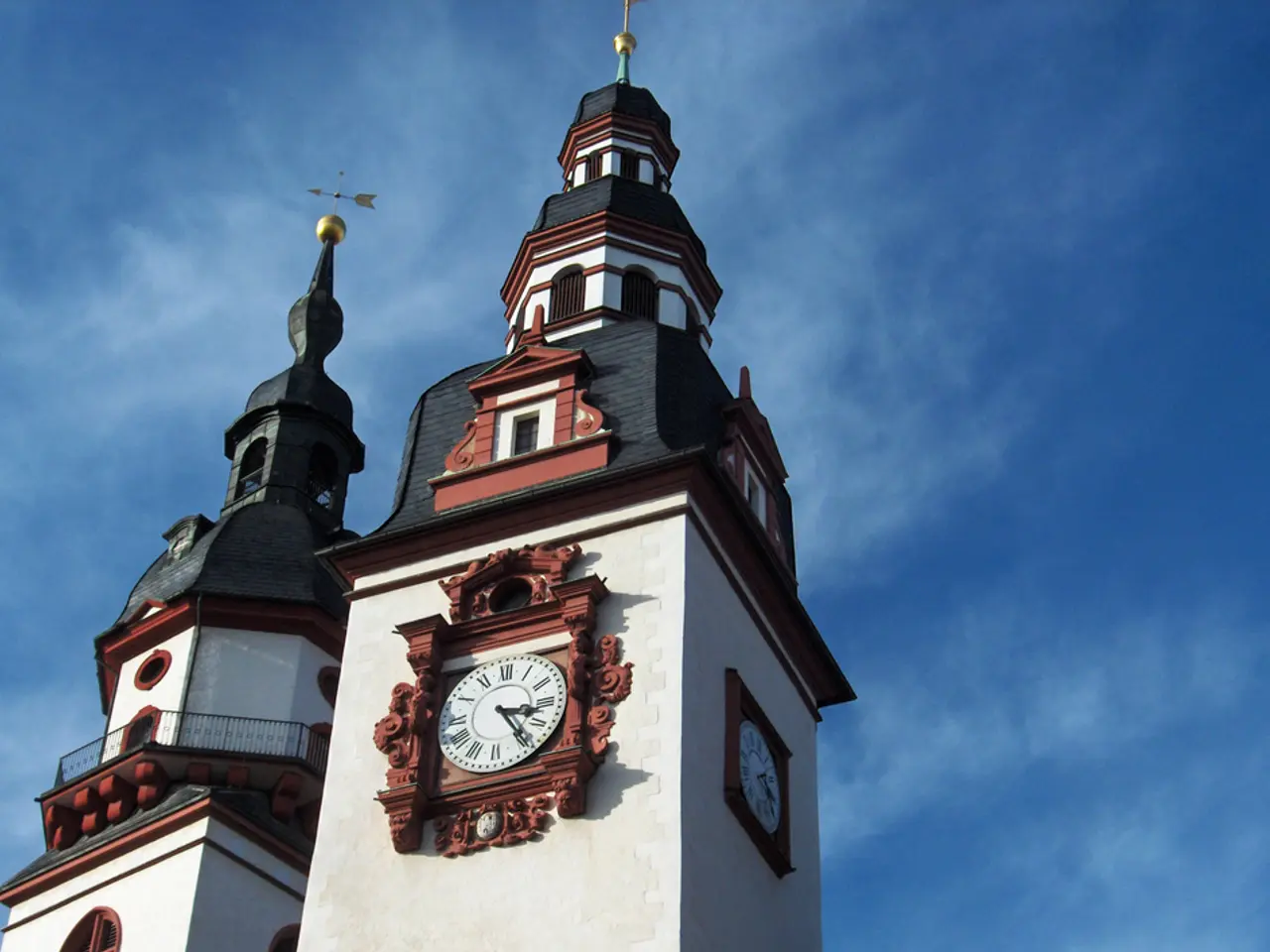 In the foreground of this image, there is a building and a clock on it. On the top, there is the...