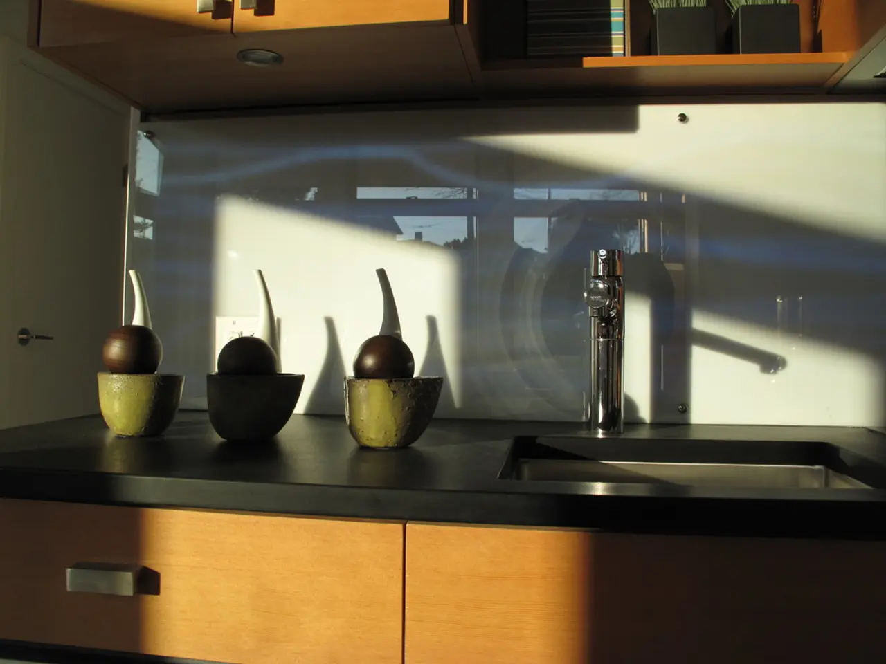 In the image there is a kitchen platform with cupboards. On the platform there is a wash basin and...