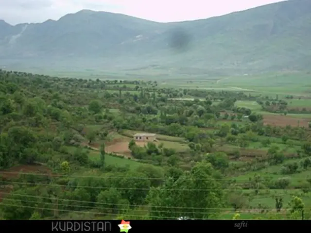 In this image I can see a logo, text, wires, trees, grass, plants, house, farms, mountains and the...