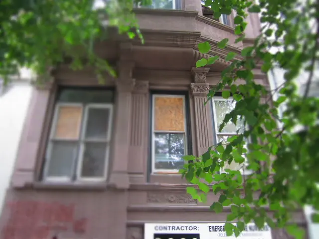 In this image there is a building having a board attached to it. On the board there is some text....