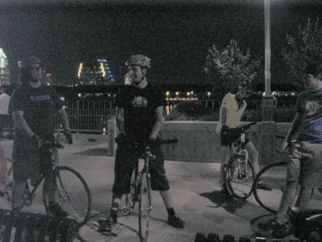 Four men are standing with their bicycles on a footpath.
