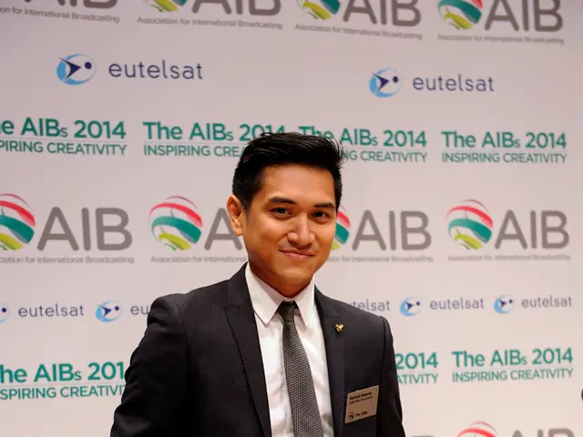 In this picture there is a person standing and smiling and he is holding the object. At the back...